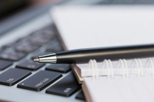 photo of pen, notebook, and computer keyboard