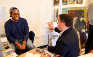 Professor Jackson sits together with a student in an advanced painting course to consult on his work