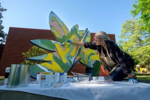 woman is painting a sculpture outside the UM Museum