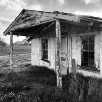Black and white photo of a small run down house.